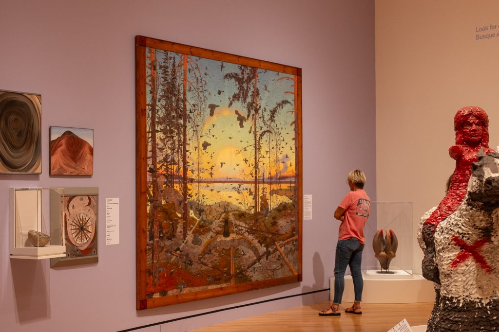 A woman in a museum looking at a large piece of art.