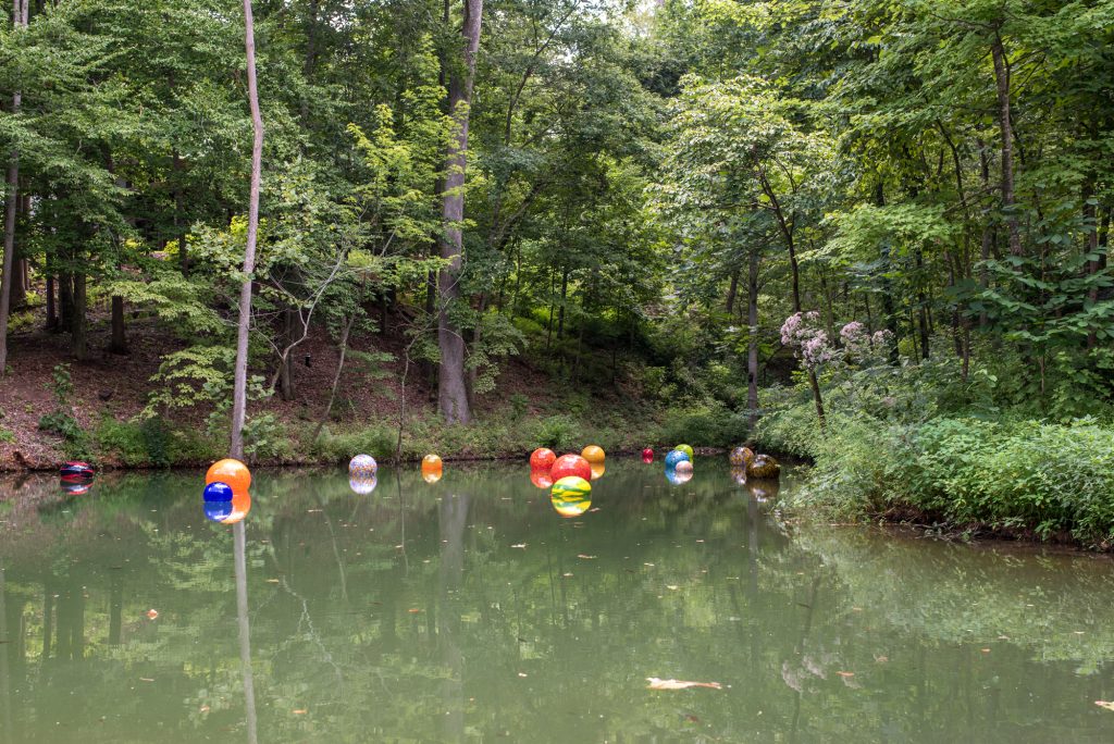 Large colorful blown glass balls floating on a pond.