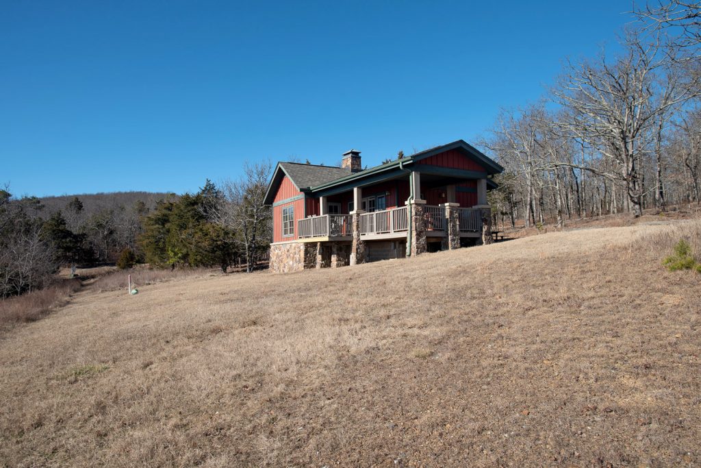 A cabin on the edge of a mountain at Mount Magazine State Park. There is a hot tub on a large deck.