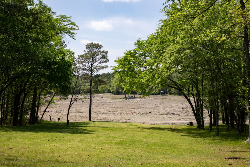 A large plowed field surrounded by trees. The is the Crater of Diamonds State Park in Arkansas where you can dig for diamonds and keep what you find.