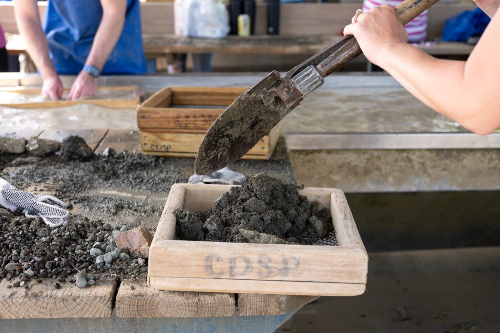 Sifting dirt in a sifter.