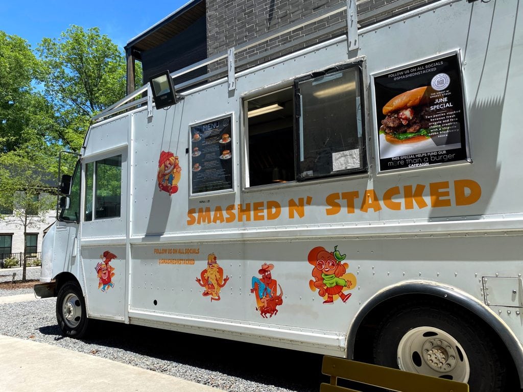 A white food truck with the words smashed n' stacked on the side. This food truck sells one of the best burgers in Little Rock. 