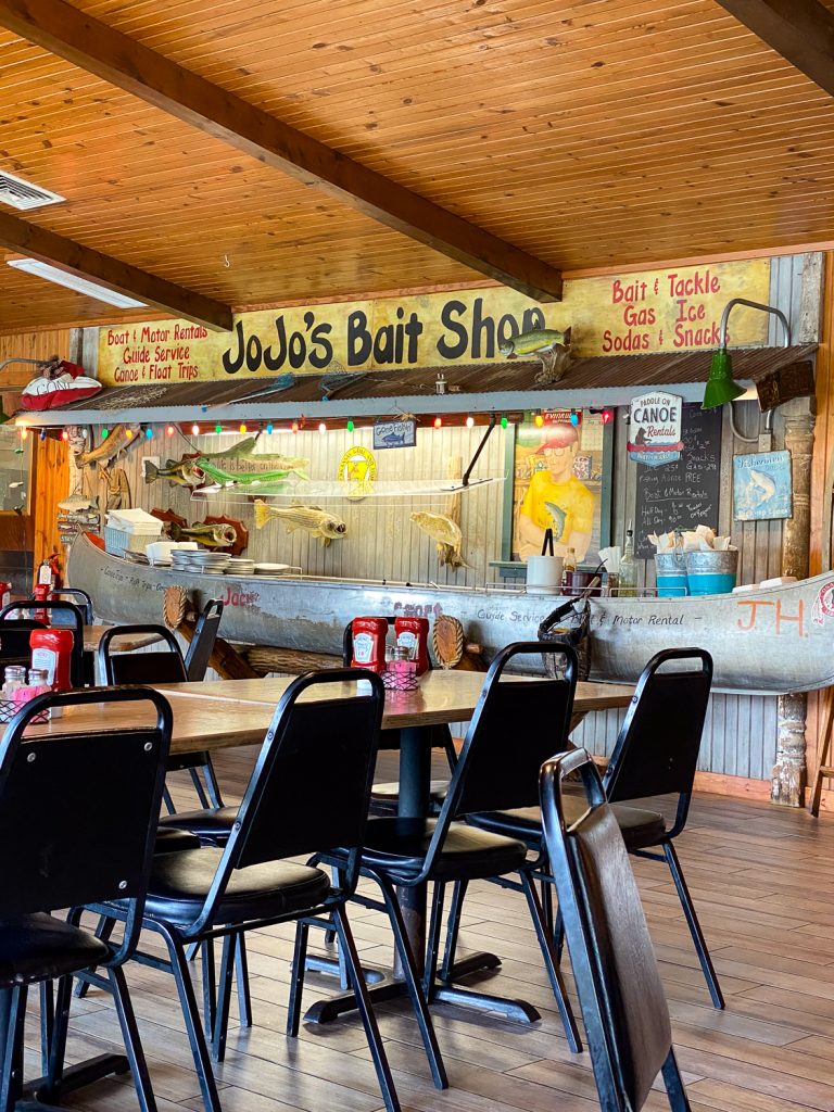A photo taken inside of Jojo's Catfish Wharf. There photo shows a full sized canoe inside of the restaurant. Above is a sign that says JoJo's Bait Shop. The canoe holds a large salad bar. 