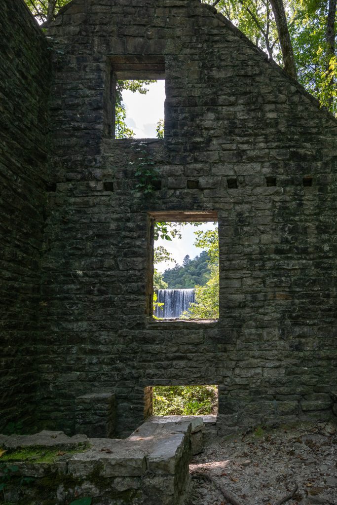 Remains of a stone wall that was once an old mill. The Mirror Lake waterfall is visible through the window of the old mill. 