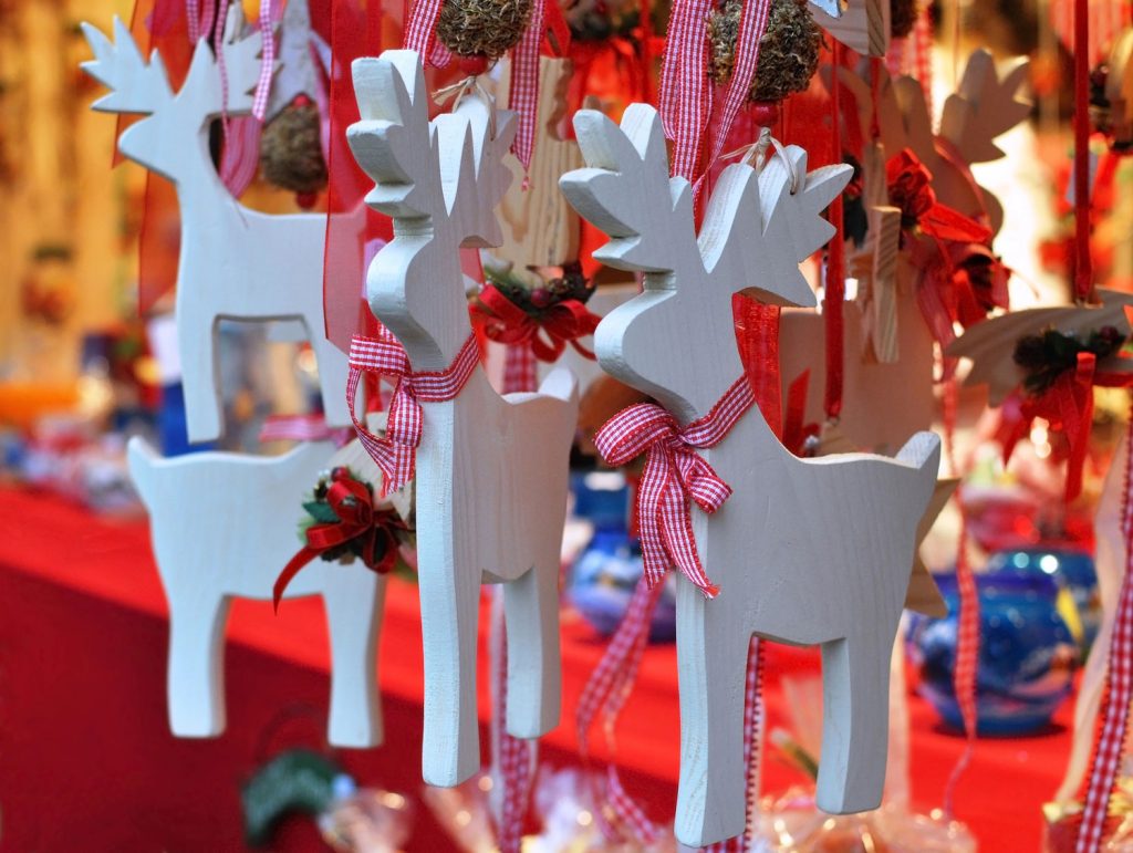 Close up of some small wooden reindeer that are hanging on a tree.