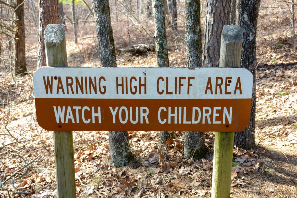 A sign that says warning high cliff area watch your children.
