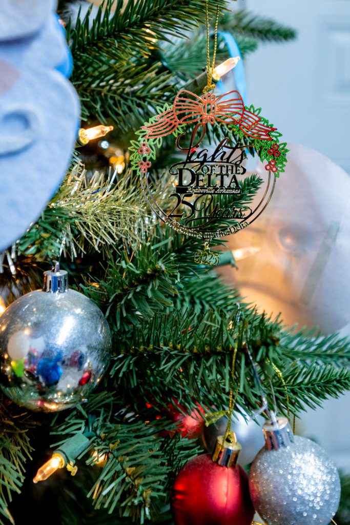 An ornament hanging on a tree that says Lights of the Delta 25 years. 2025.