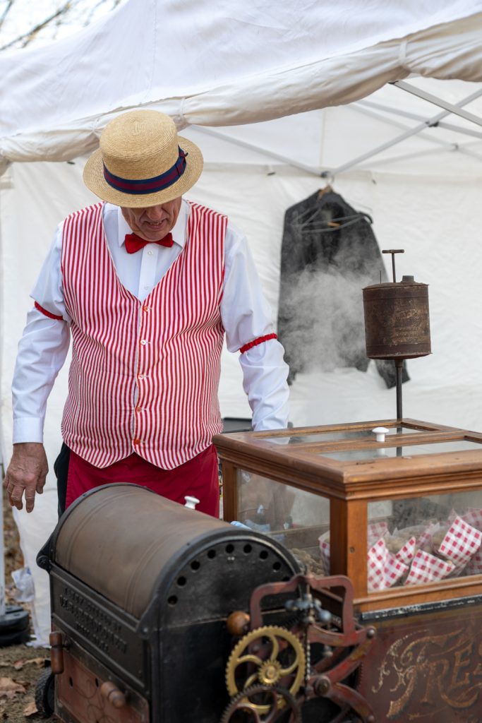 A man in an old fashioned costume roasting peanuts at the Pioneer village in Searcy Arkansas.