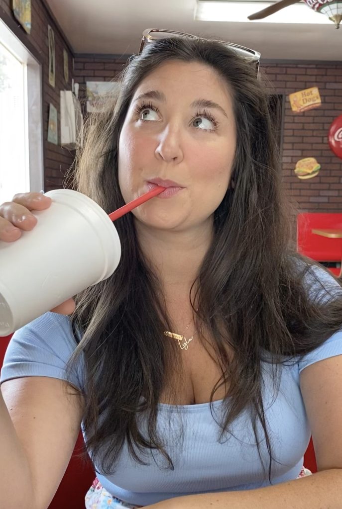 A young woman in the Dairyette drinking a milk shake.