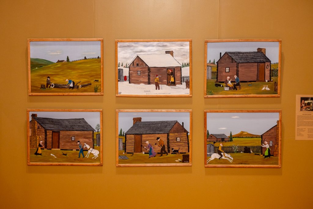 A series of six pictures in an art gallery showing a farmstead in Arkansas in all seasons