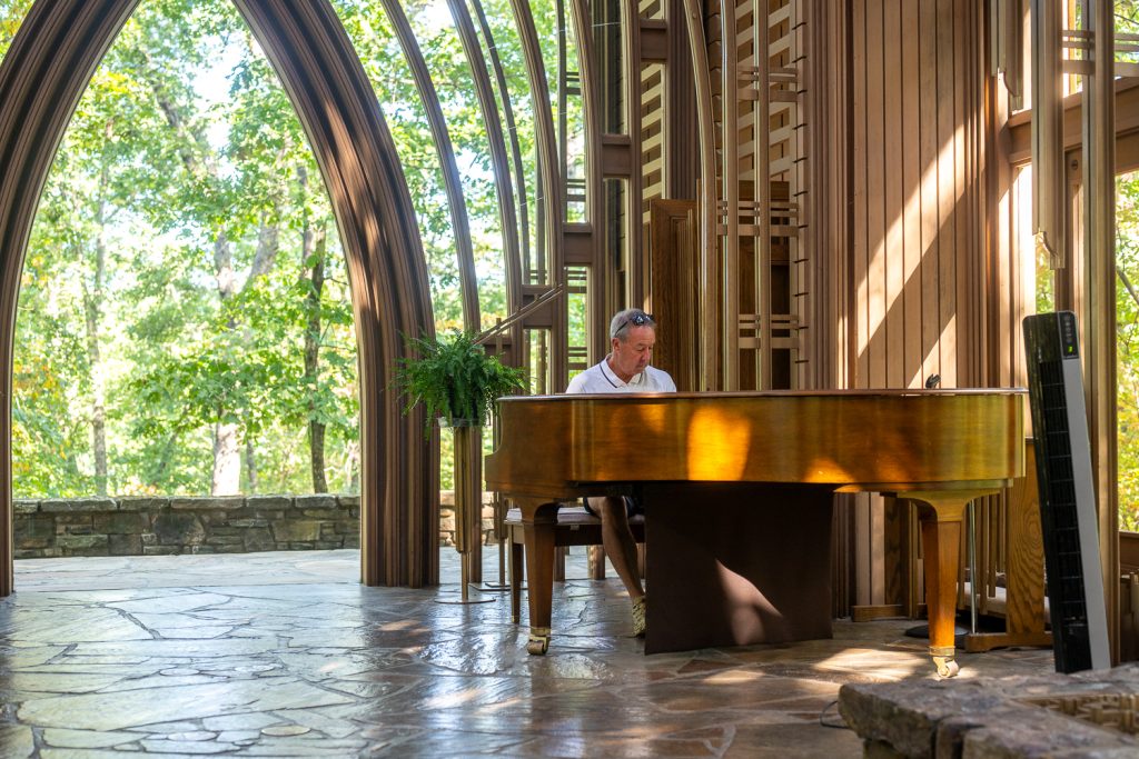Man playing the piano in Mildred Cooper glass chapel